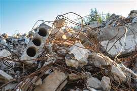 An image showing assorted construction waste in a pile, including broken pieces of concrete and twisted reinforcement bars.