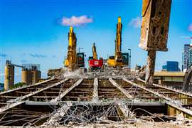 Three excavators atop a bridge carry out demolition works