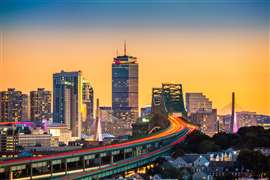 Sunset skyline showing a US city with traffic flowing over a bridge.