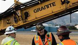 Three Granite Construction workers stand on a construction site