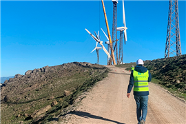 A site operative walking towards a wind turbine being dismantled