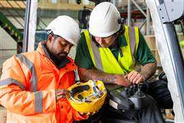 Two construction workers inspect a hard hat