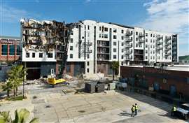 A high reach excavator dismantles the fire ravaged Rise Roro apartment complex.