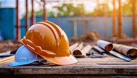 Two hard hats, one resting on top of the other, on a construction site.