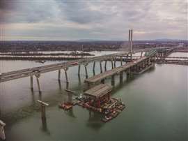 An in-river section of the Champlain Bridge being removed uses barges and jacking systems