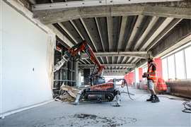 A worker uses a demolition robot