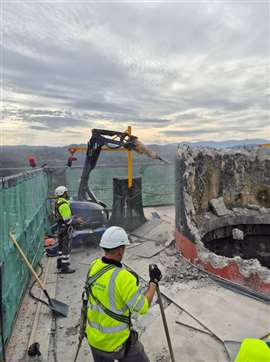 Demolition workers and a demolition robot on the platform working at height