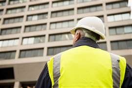 Obrero de la construcción/inspector de edificios inspeccionando un edificio alto