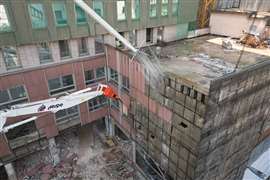 A high reach excavator demolishes the flat-roofed addition of the Hotel Michelangelo in Milan