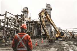 A worker on site with a high reach excavator
