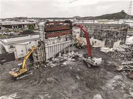 Aerial shot of two high reach machines demolishing one of the site's structures.