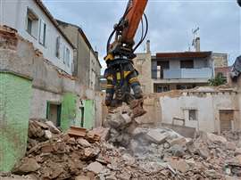 Escavadeira com tesoura demolindo prédio urbano