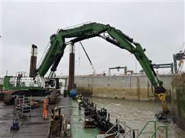 Excavadora trabajando en el puerto demoliendo un muro de muelle de hormigón