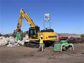 A yellow Komatsu excavator next to a pile of rubble