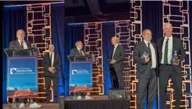 The two men on stage shaking hands and posing for pictures
