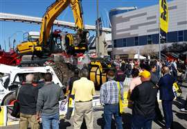 Audience wathcing yellow excavator at trade show