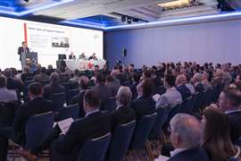 Sala con filas de personas observando al presentador en el escenario.