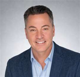 Headshot of man in light blue shirt and blue blazerlooking at the camea