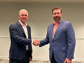 Two men shaking hands looking towards the camera