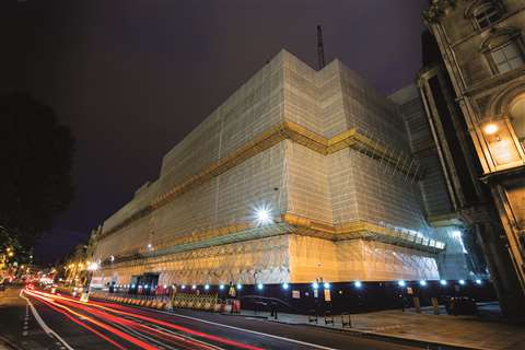An high-rise structure with safety scaffolding around it, at night