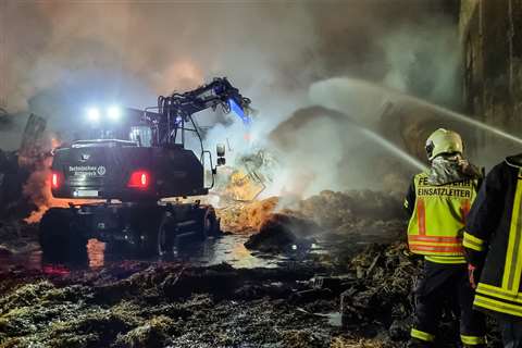 Operatives use water hoses to suppress dust as the Atlas 140W blue excavator dismantling the building in Baden-Württemberg, Germany