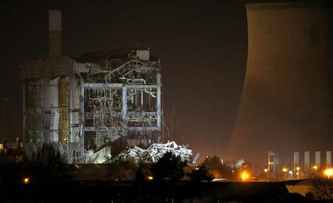 Part of a collapsed building is illuminated by the emergency services as they work at the decommissioned Didcot A power station in central England