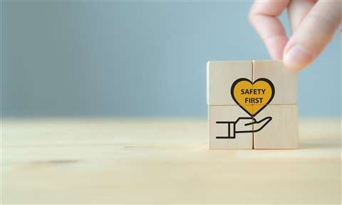 A hand stacks wooden block with a heart over hands symbol on it